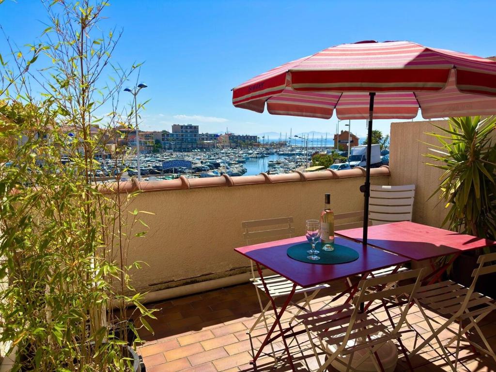 een tafel met een parasol en twee glazen op een balkon bij Tokelau - Vue Mer in Sausset-les-Pins