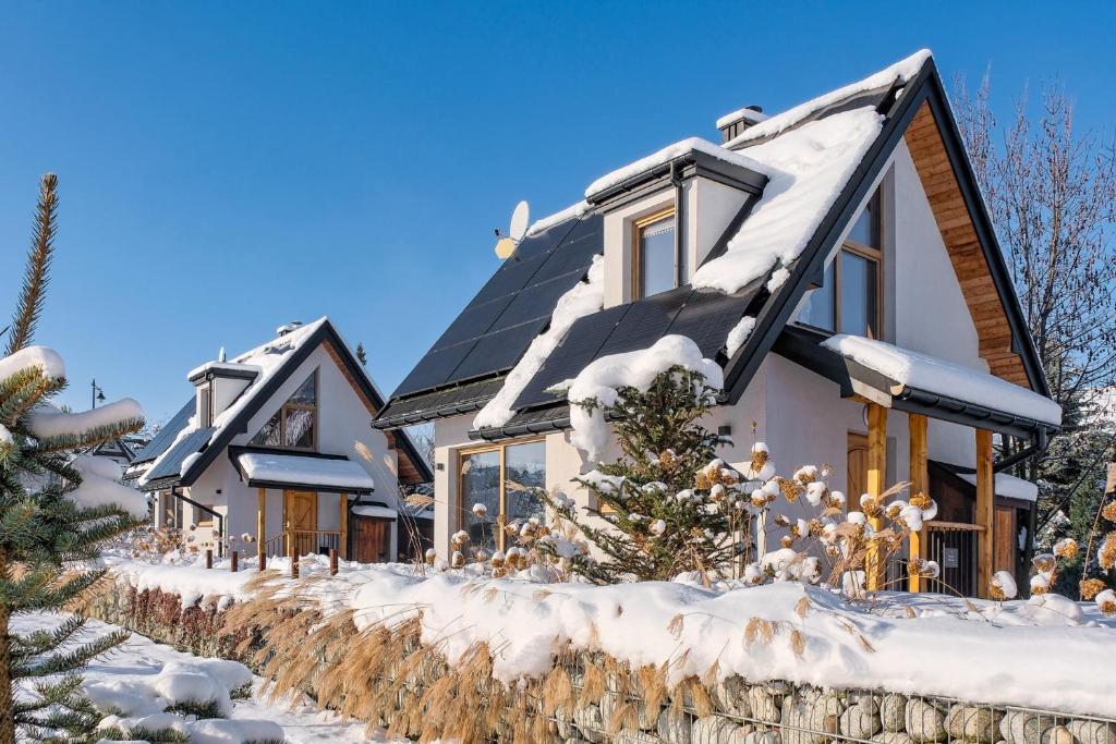 una casa con techo solar en la nieve en Osada Białka Tatrzańska - apartamenty & domki z ogrodem dla rodzin Odkryj-Bialke, en Białka Tatrzanska