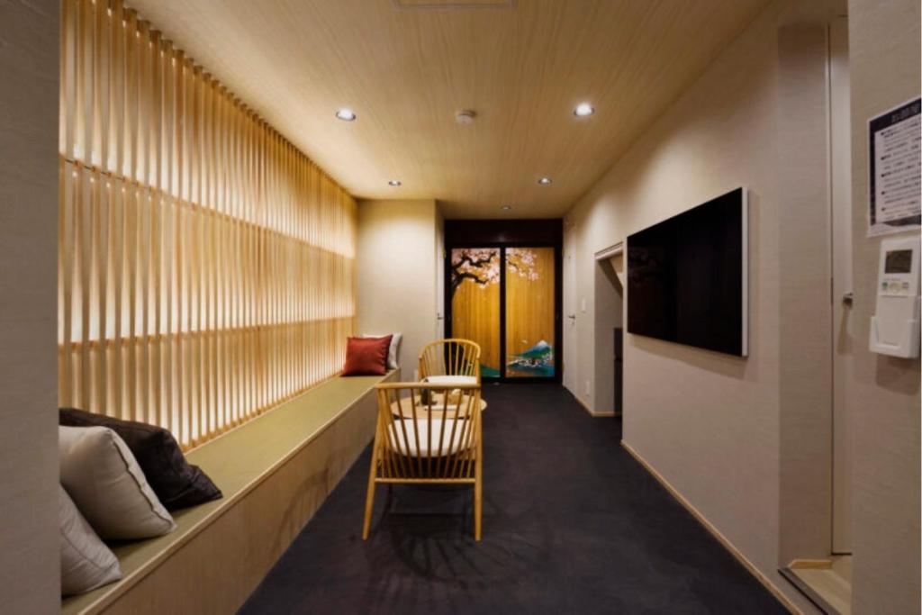 a room with a bench with a television and a chair at NEW Hotel Komugi Skytree - modern Japanese-style guesthouse near Asakusa & Skytree 3mins, whole house rental perfect for large groups up to 14pax in Tokyo