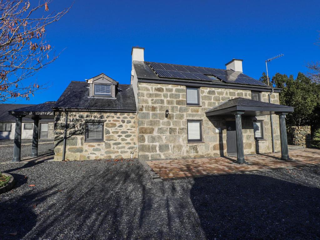 a stone house with solar panels on it at Ty'n Lon Farm in Pwllheli