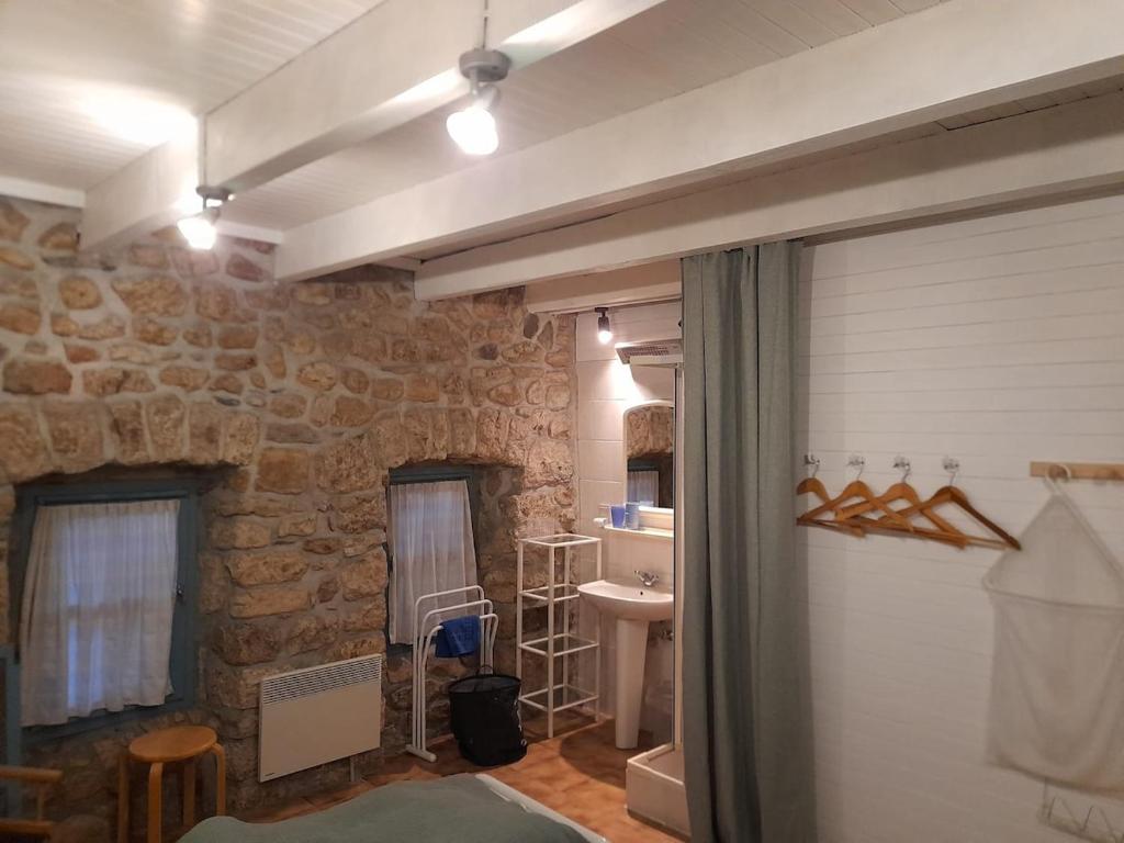 uma casa de banho com uma parede de pedra e um lavatório em Julie's House em Chanéac