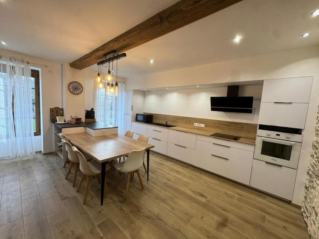 a kitchen with a wooden table and white cabinets at Au plaisir de l'ivoie in Le May-sur-Èvre