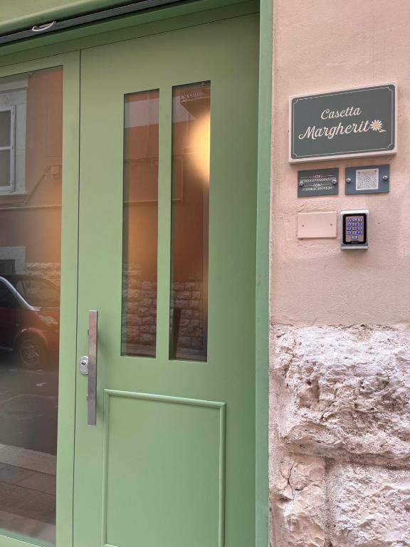 a green door of a building with a sign on it at Casetta Margherita in Bisceglie