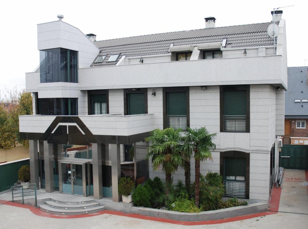 a white building with palm trees in front of it at Hostal Los 5 Pinos in Madrid