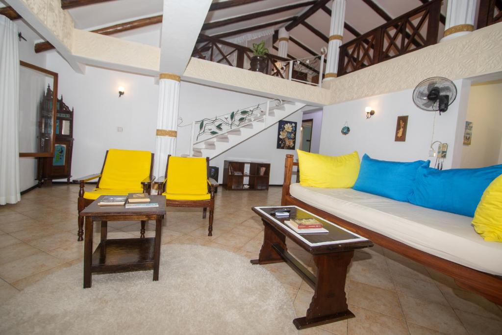 een woonkamer met een bank en 2 gele stoelen bij The Malindi Mansion in Malindi