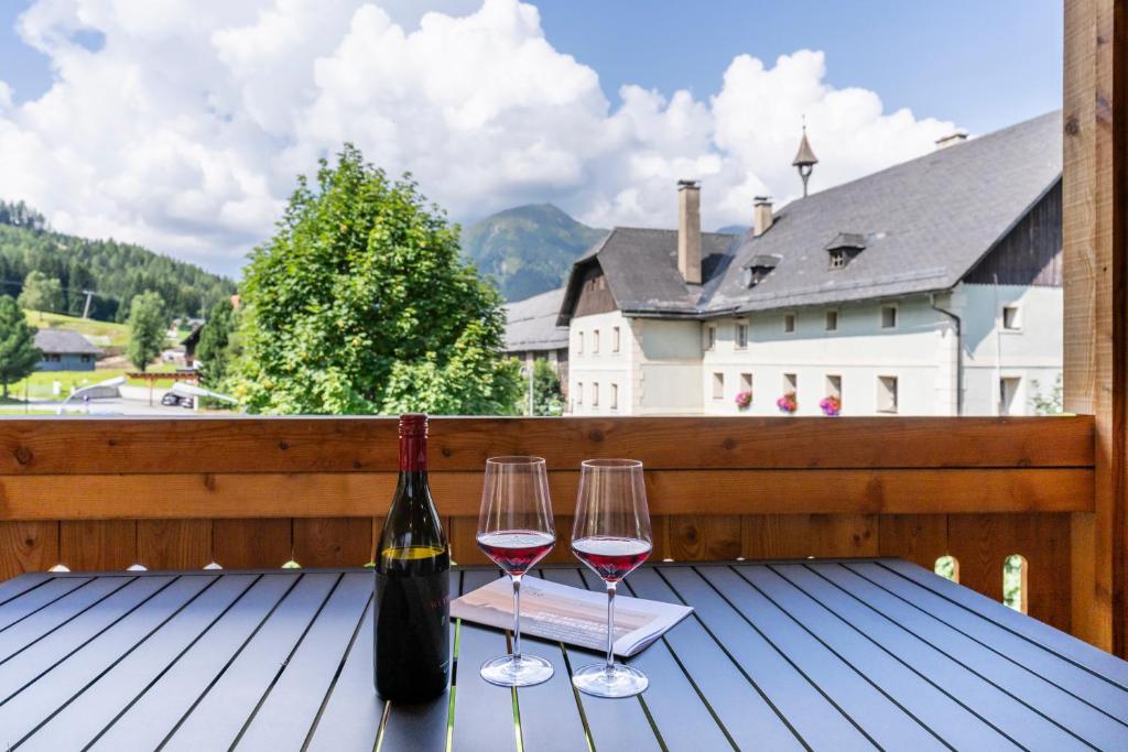 two glasses of wine sitting on a wooden deck at Dorfplatzl Suite in Hohentauern