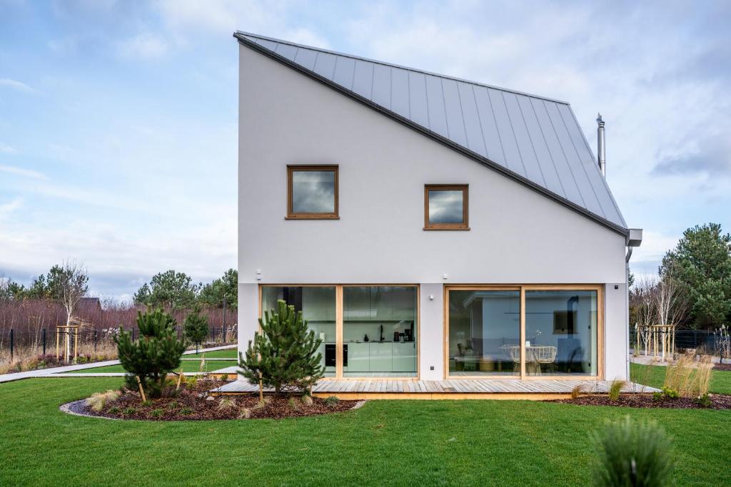 a white house with a black roof at Miło in Lubiatowo