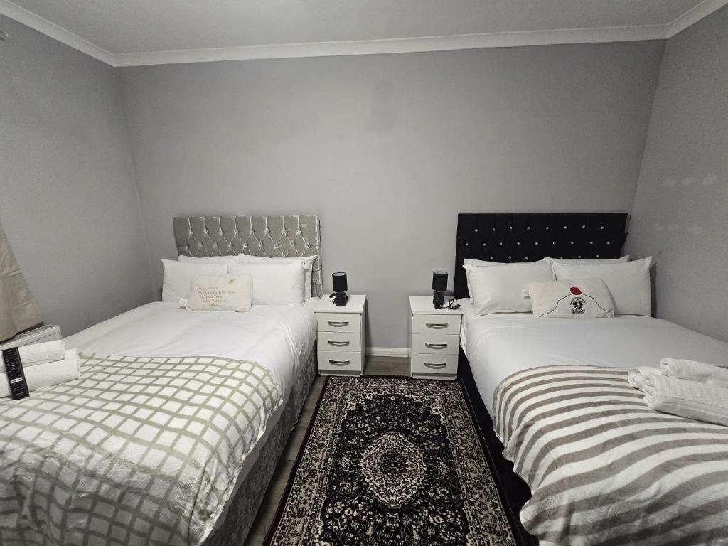 two twin beds in a room with white walls at Heathrow roomzzzz BnB in Hayes