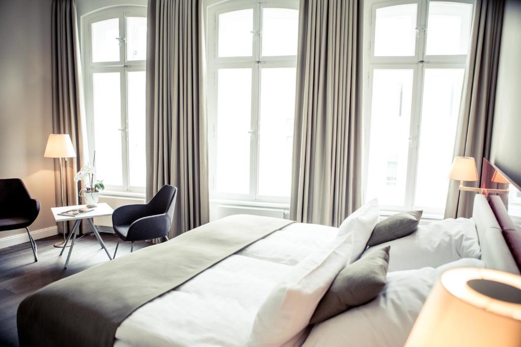 a bedroom with a large white bed with windows at Weinhaus Uhle in Schwerin