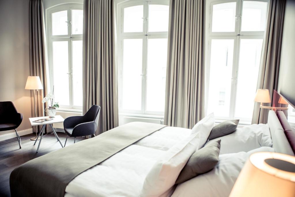 Schlafzimmer mit einem großen weißen Bett und Fenstern in der Unterkunft Weinhaus Uhle in Schwerin