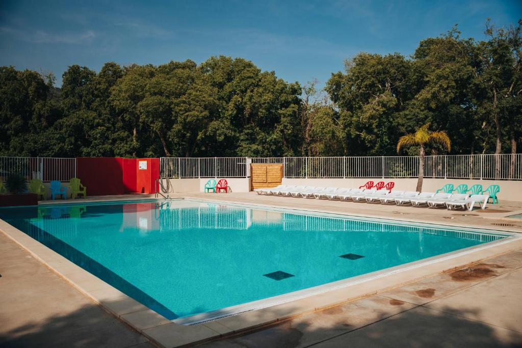 an empty swimming pool with chairs and a fence at Camping le Rancho in Argelès-sur-Mer