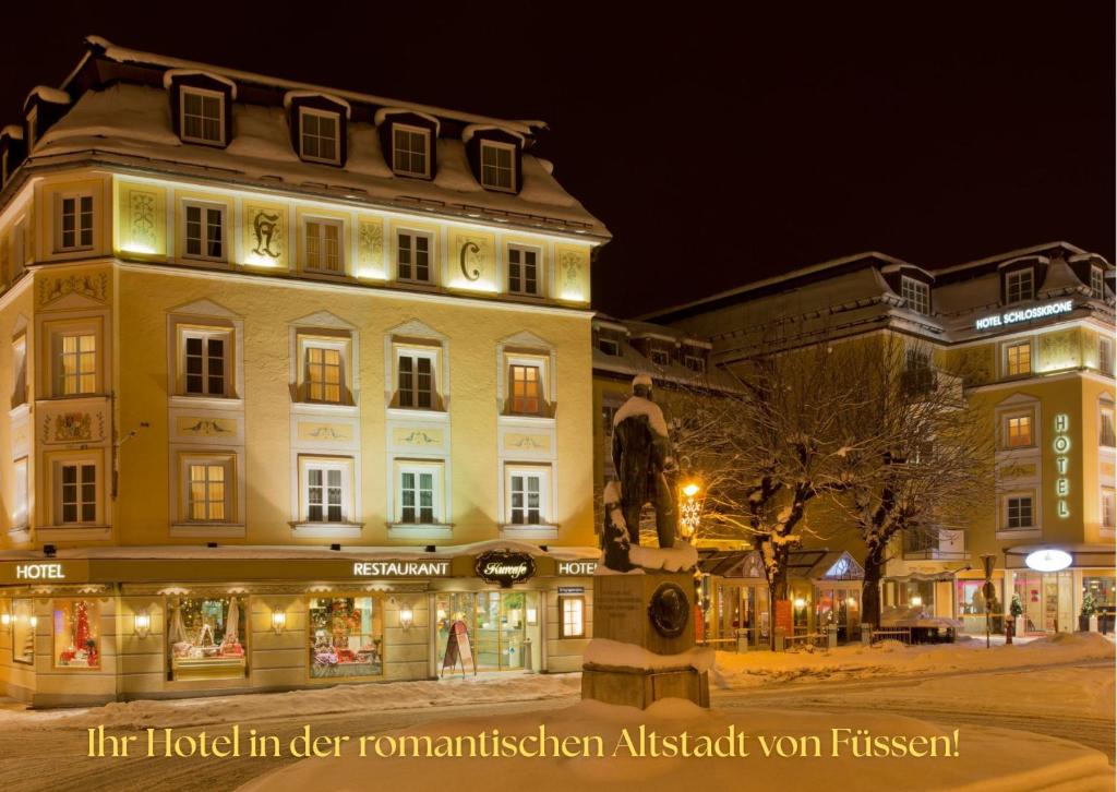 a building with a statue in front of it at night at Hotel Schlosskrone in Füssen
