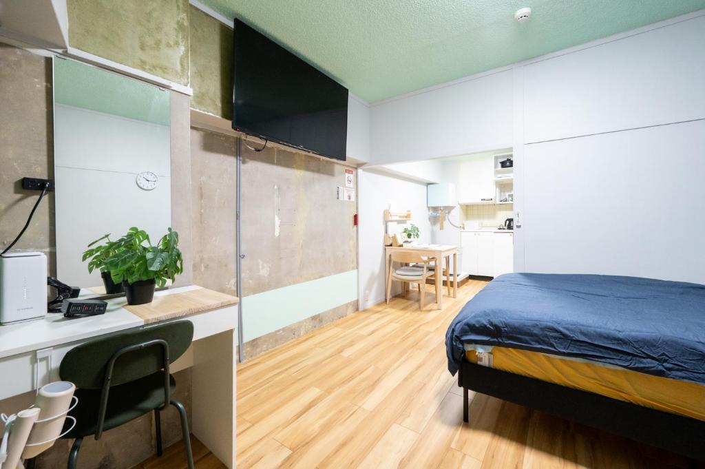 a bedroom with a bed and a desk and a kitchen at yadobankharuyoshi201 in Fukuoka