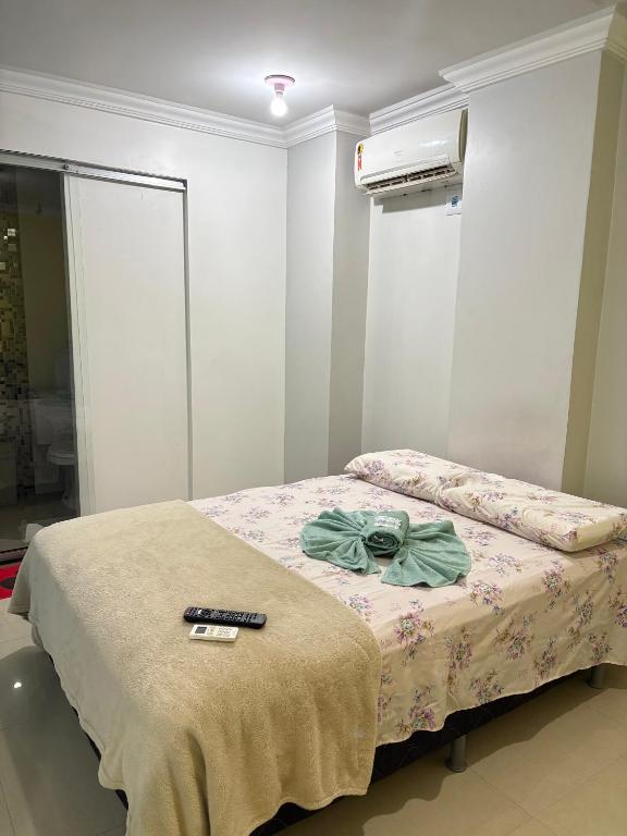 a bedroom with a bed with a remote control on it at Quarto privado próximo ao centro 10 in Manaus