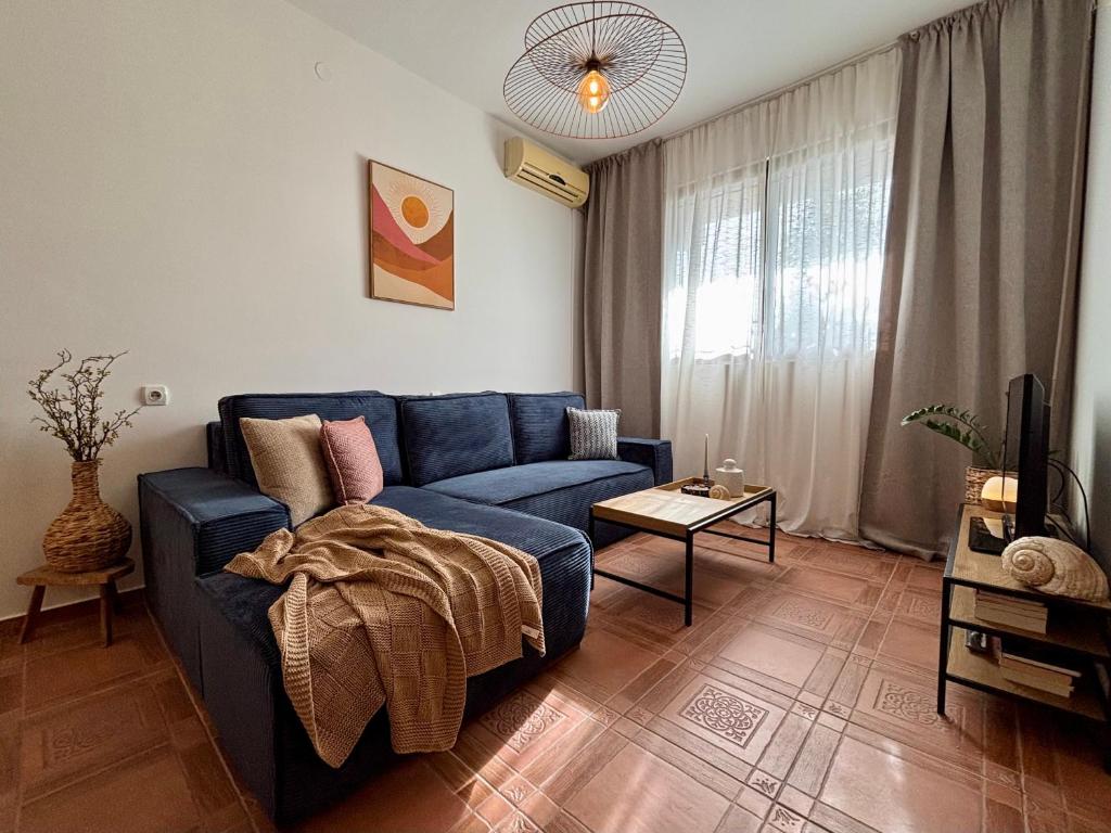a living room with a blue couch and a tv at Flora Apartment - near the sea in Bar, Susanj