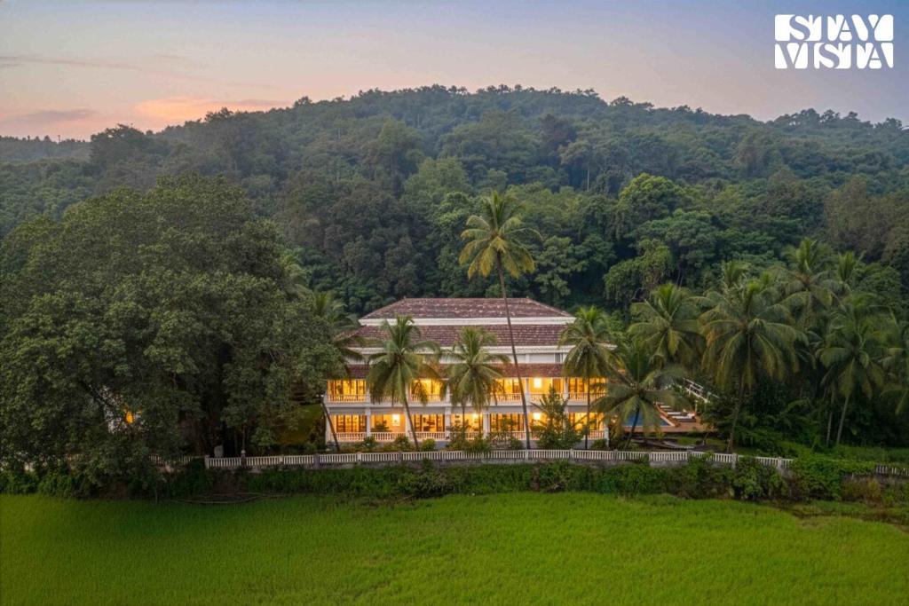 um grande edifício em frente a um campo verdejante em StayVista at Casa Verano with Pool, BBQ em Siolim