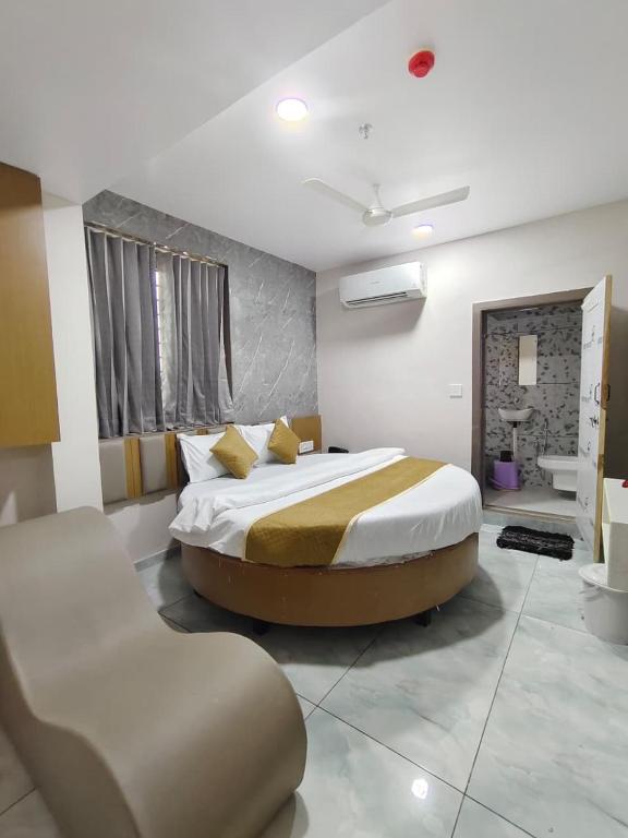 a bedroom with a large bed and a chair in it at Hotel Metro in Himatnagar