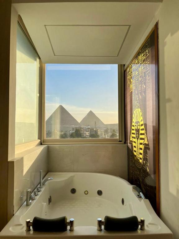 a bath tub in a bathroom with a large window at Nefertiti Royal Hotel in Cairo
