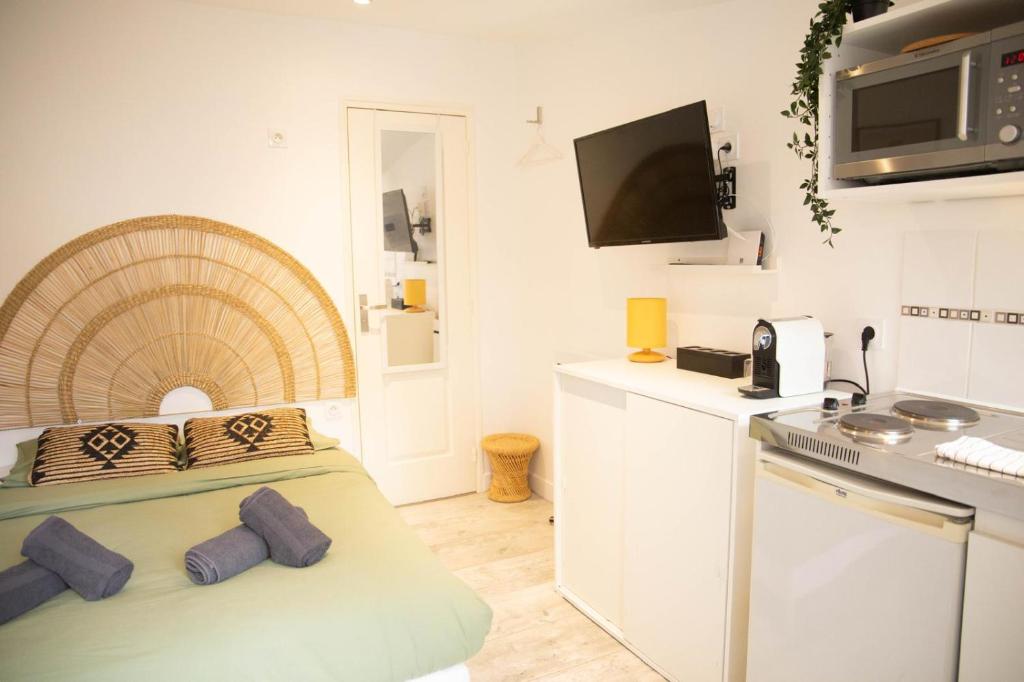 a small white kitchen with a bed and a microwave at Charmant Studio avec parking Résidence Zénith in Caen