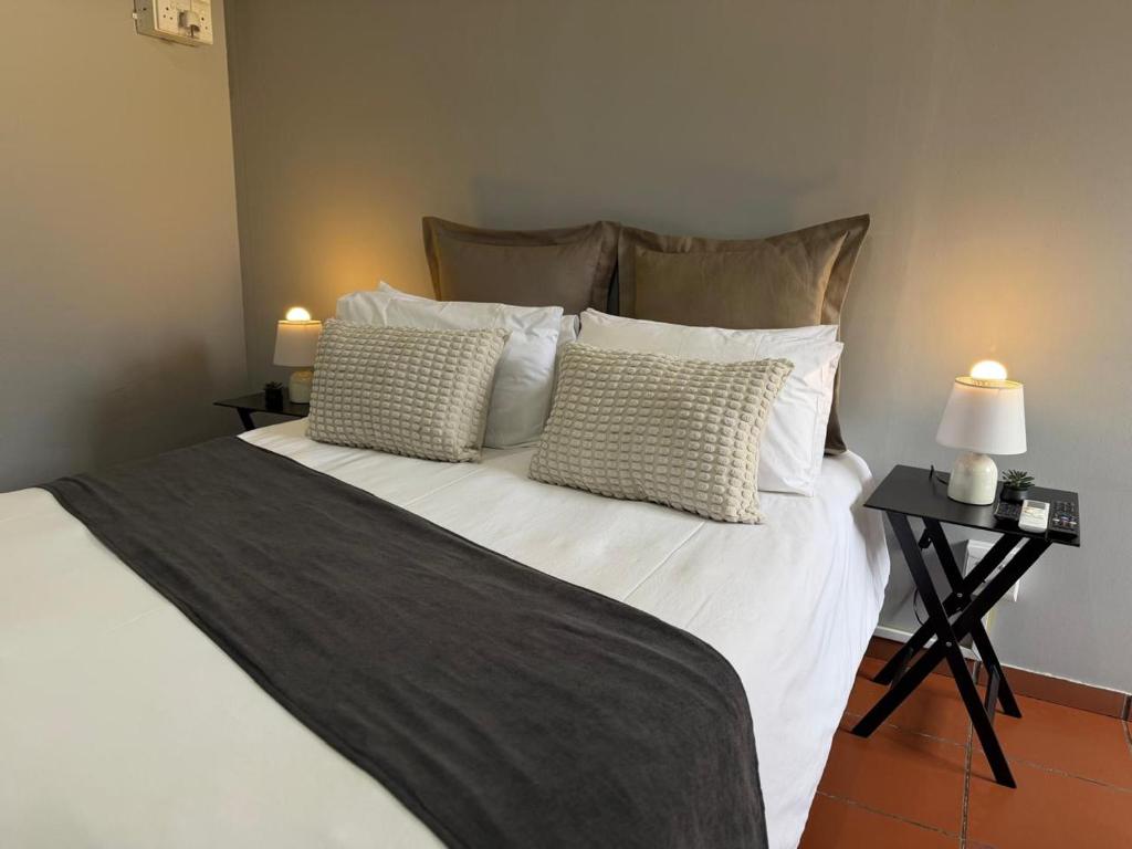 a bedroom with a bed with white sheets and pillows at 4 On Susanna in Kimberley