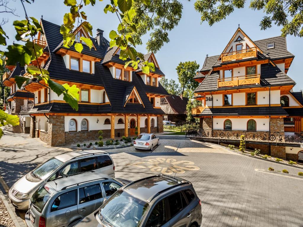a large house with cars parked in front of it at TatryTop Zakopiańskie Tarasy Premium & SPA in Zakopane