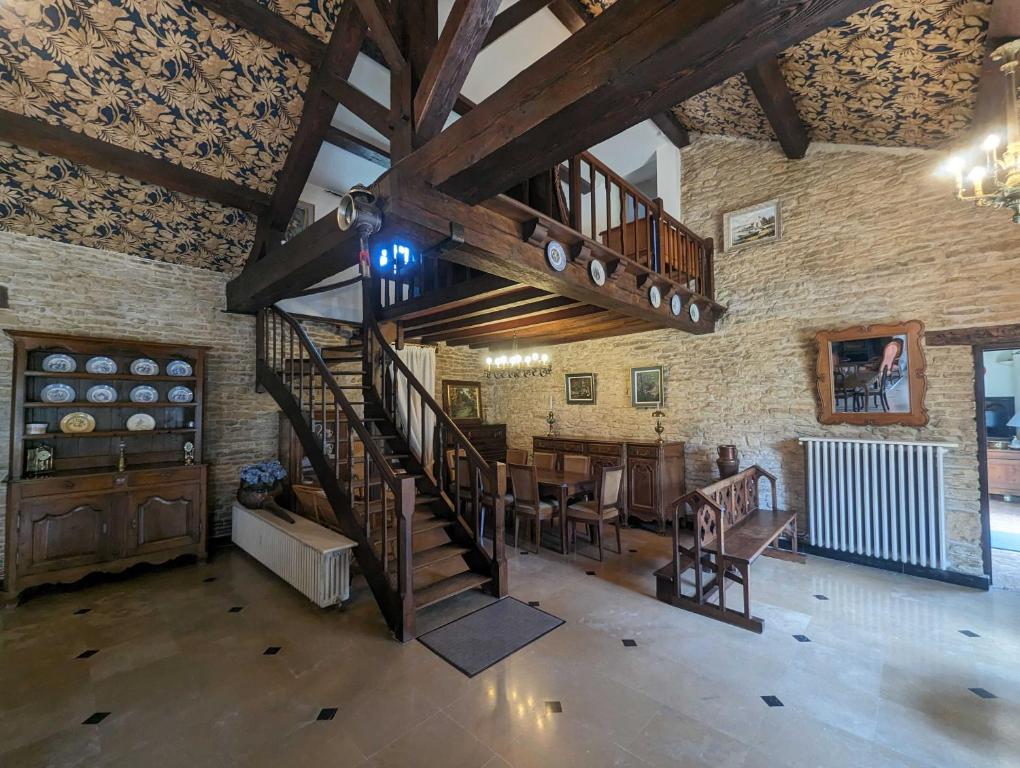 een grote kamer met een houten trap en een eetkamer bij Villa antigone in Vaux-sous-Aubigny