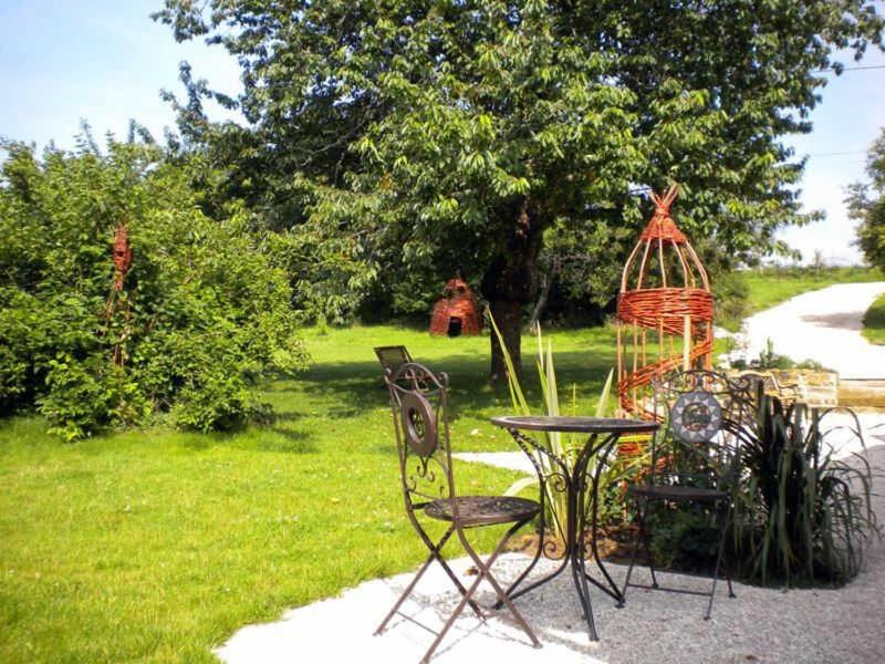 une table et des chaises dans une cour avec une cage pour oiseaux dans l'établissement Le routoir, à Fayl-Billot