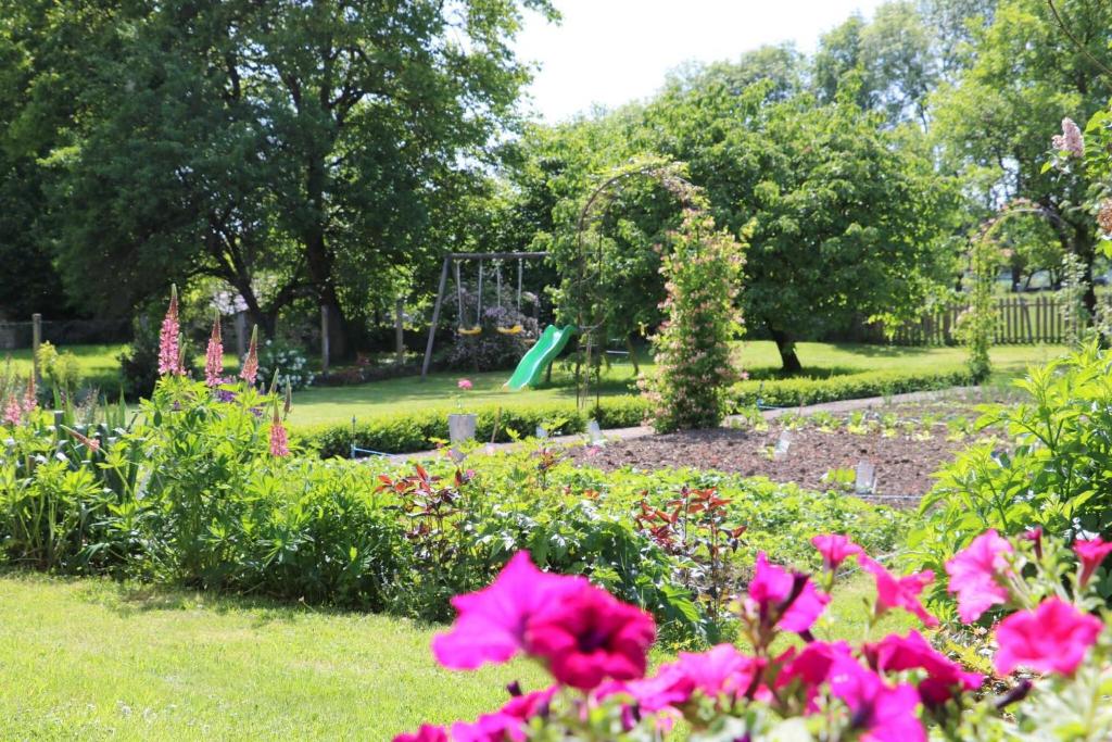ein Park mit einem Spielplatz im Hintergrund und rosa Blumen in der Unterkunft Gite de la fontaine in Saint-Blin