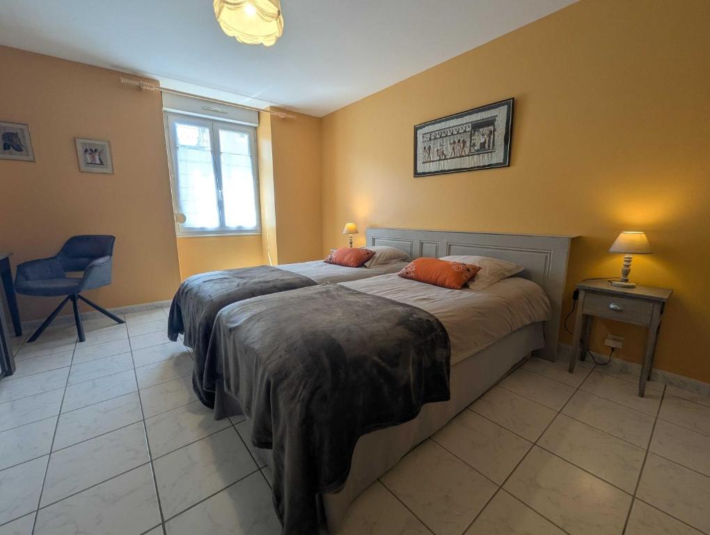 een slaapkamer met twee bedden en een stoel en een raam bij Gite simone de beauvoir in Châteauvillain