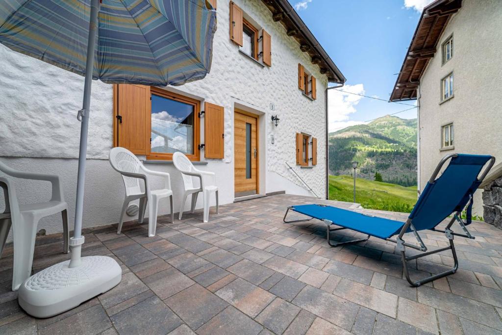 patio z krzesłami, parasolem i ławką w obiekcie Ospitalità Diffusa Laste Dolomites Cèsa del Bèrba Jaco w mieście Colle Santa Lucia