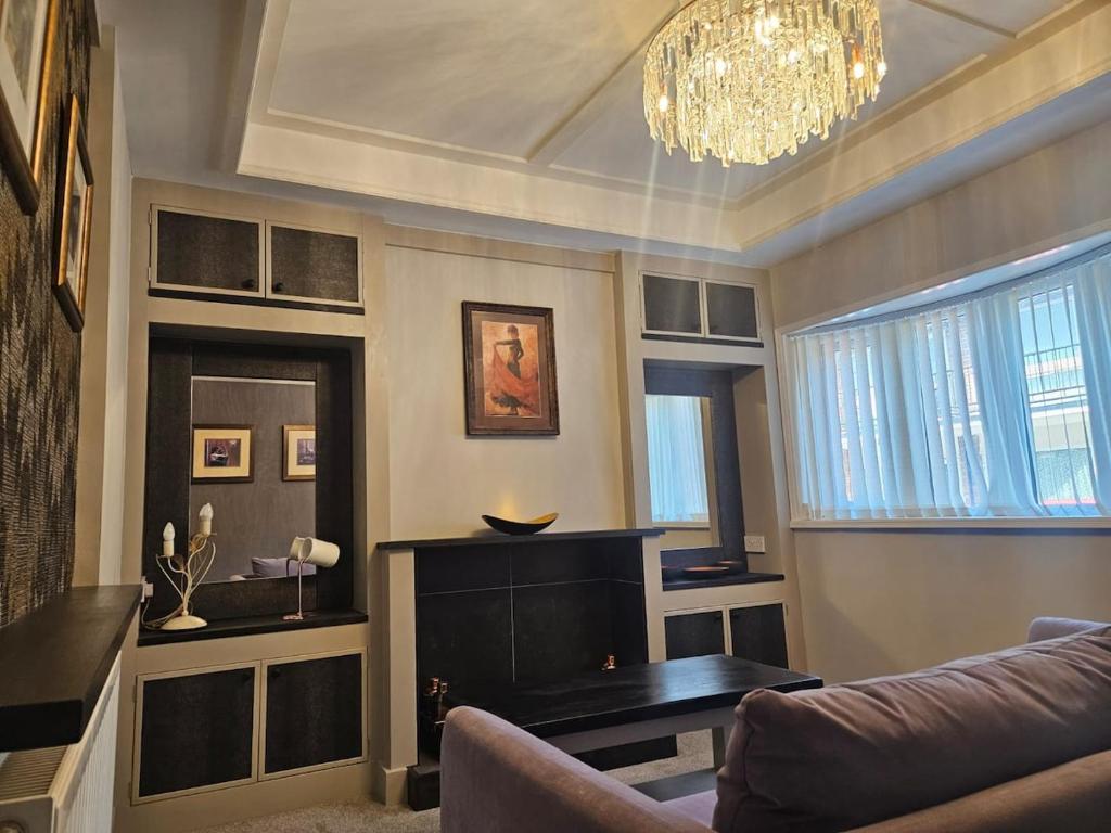een woonkamer met een bank en een kroonluchter bij Tastefully decorated modern home in Nantwich
