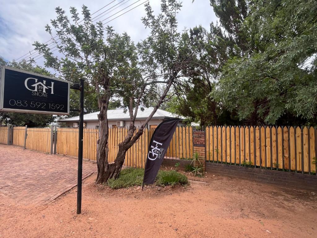 a sign in front of a fence next to a tree at 39 Shone GH in Postmasburg