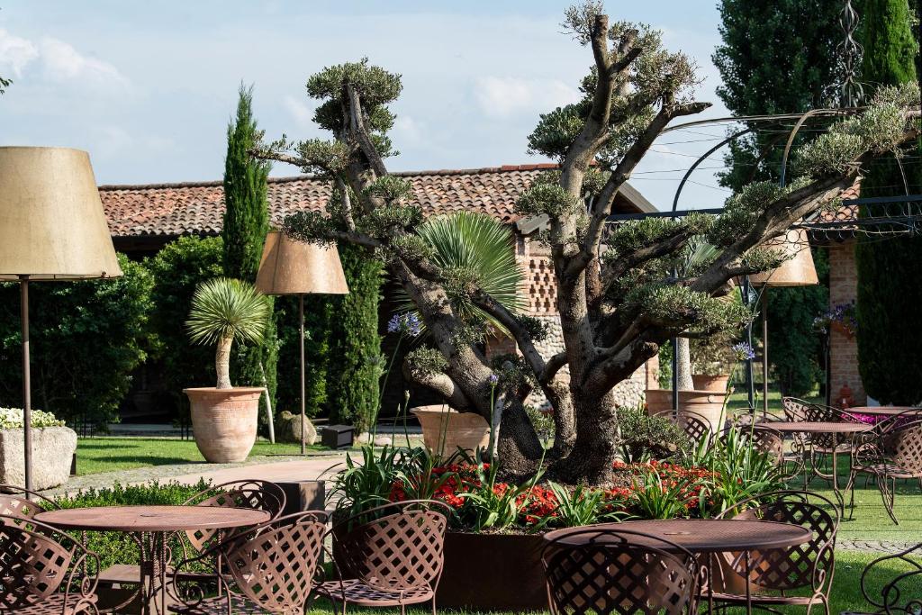 La Colombera Ristorante - Albergo في Castrezatto: حديقة فيها طاولات وكراسي وشجرة