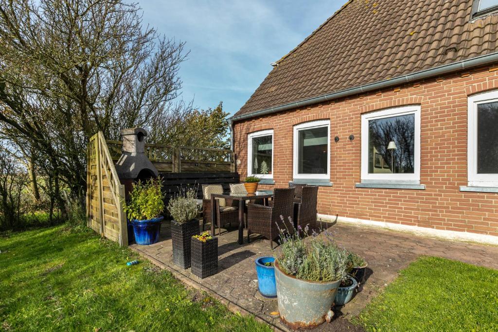 eine Terrasse eines Hauses mit einem Tisch und Stühlen in der Unterkunft Lehmhuus in Klanxbüll