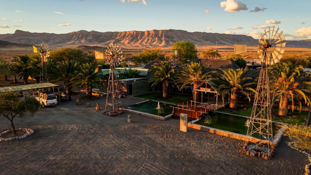 an aerial view of a resort with palm trees and a mountain at Tsauchab River Camp in Sesriem