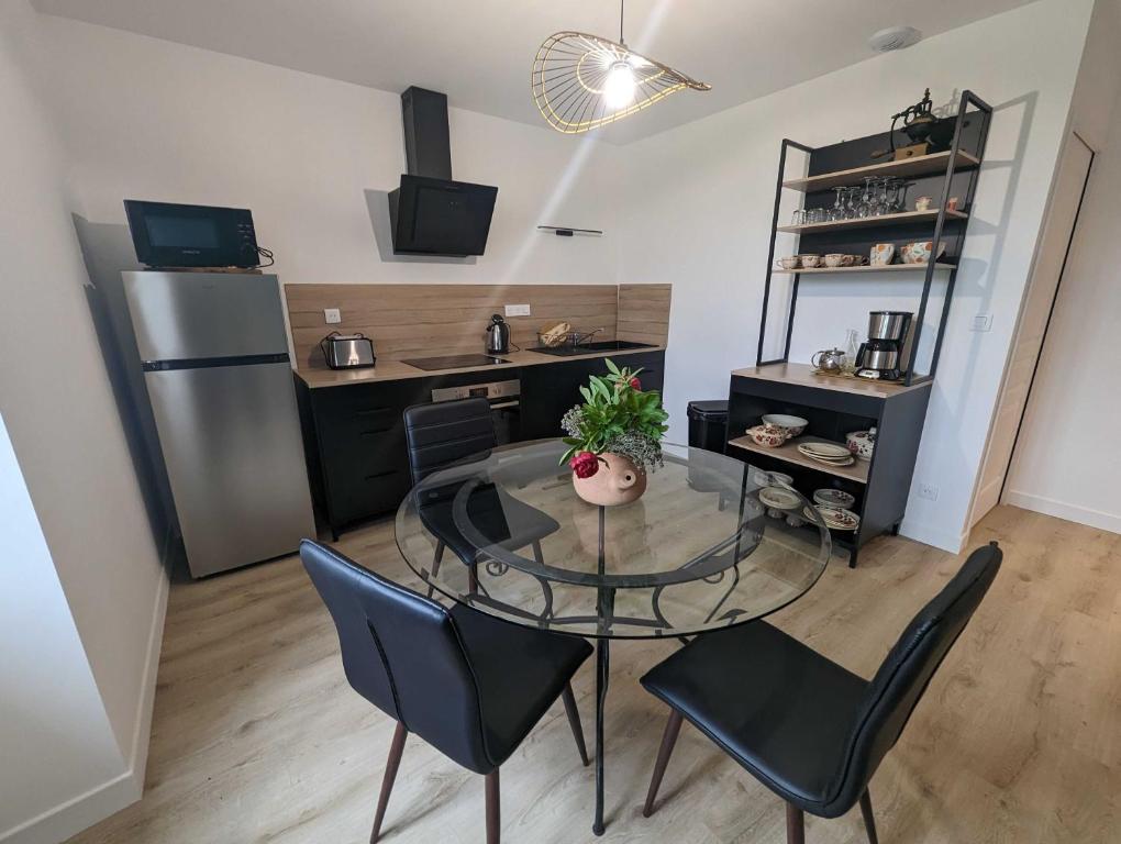 een keuken en eetkamer met een glazen tafel en stoelen bij Le nancery in Langres
