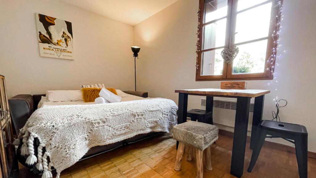 um quarto com uma cama, uma mesa e uma janela em Loft Serenitat Montana Park em Enveitg