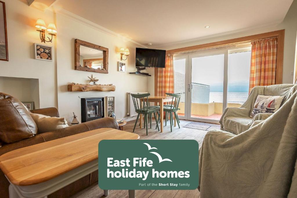 uma sala de estar com um sofá e uma mesa em Rockhopper Cottage Lower Largo em Lower Largo