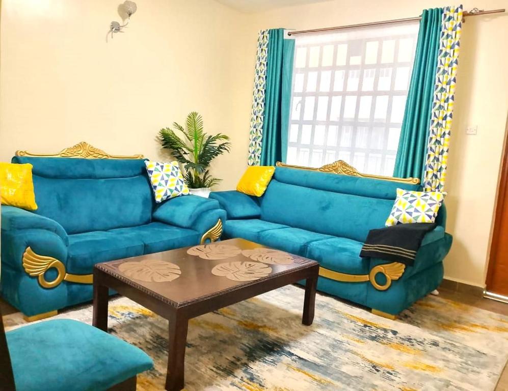 a living room with blue couches and a coffee table at Rukeja-PKK Homestays Nanyuki Town in Nanyuki