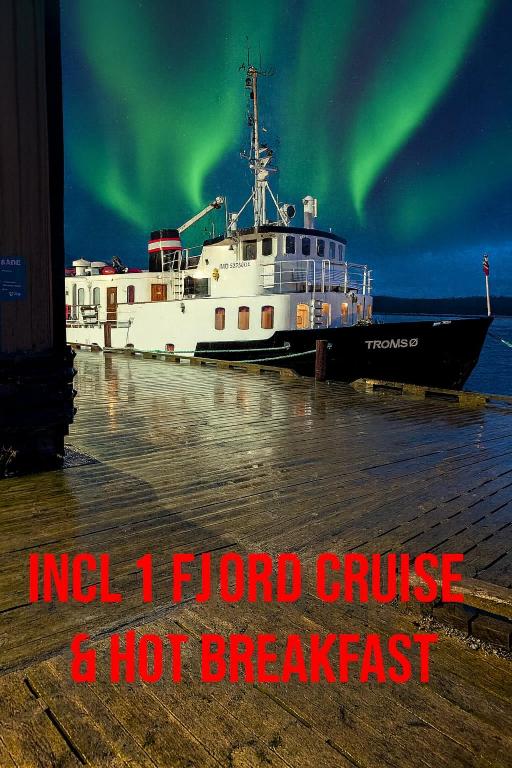 a boat is docked in the water under the aurora at Norwegian Fjord Explorer Line in Tromsø