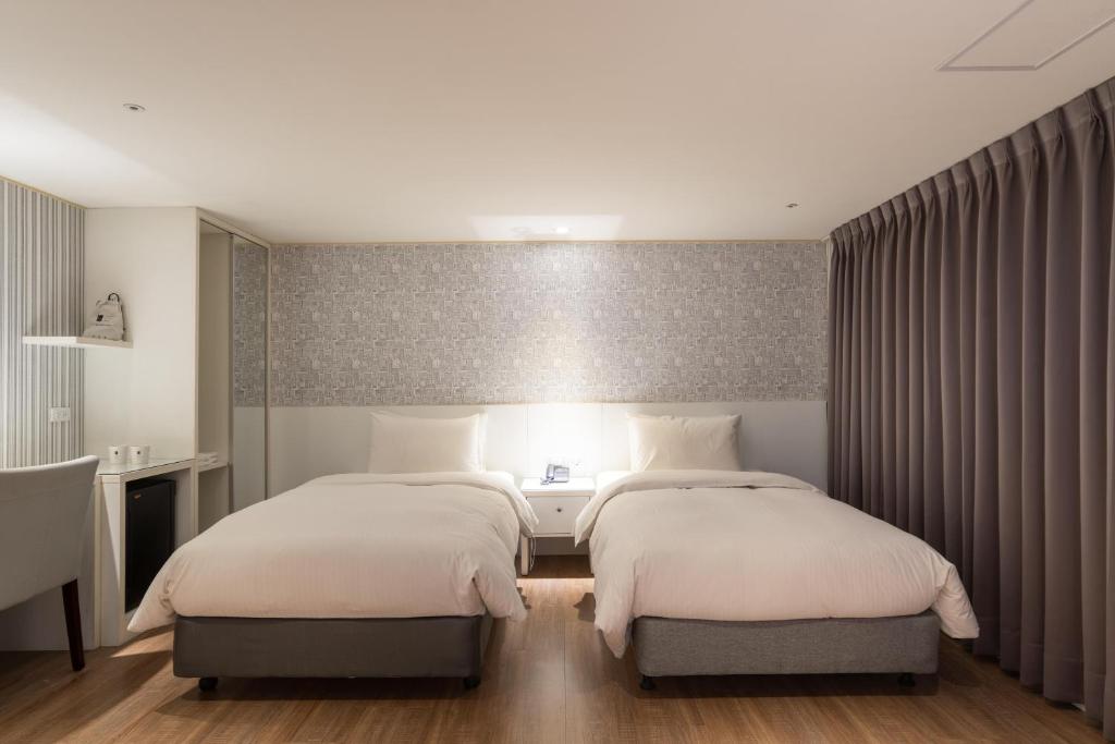 a bedroom with two beds and a desk in it at 雋格大飯店 Elence Hotel in Taichung