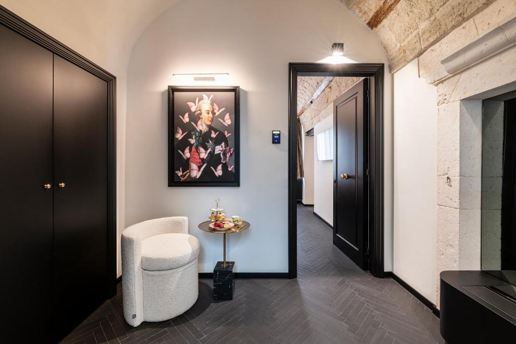 Dimora San Nicola Charming Suite في كونفيرسانو: ممر به كرسي أبيض وطاولة