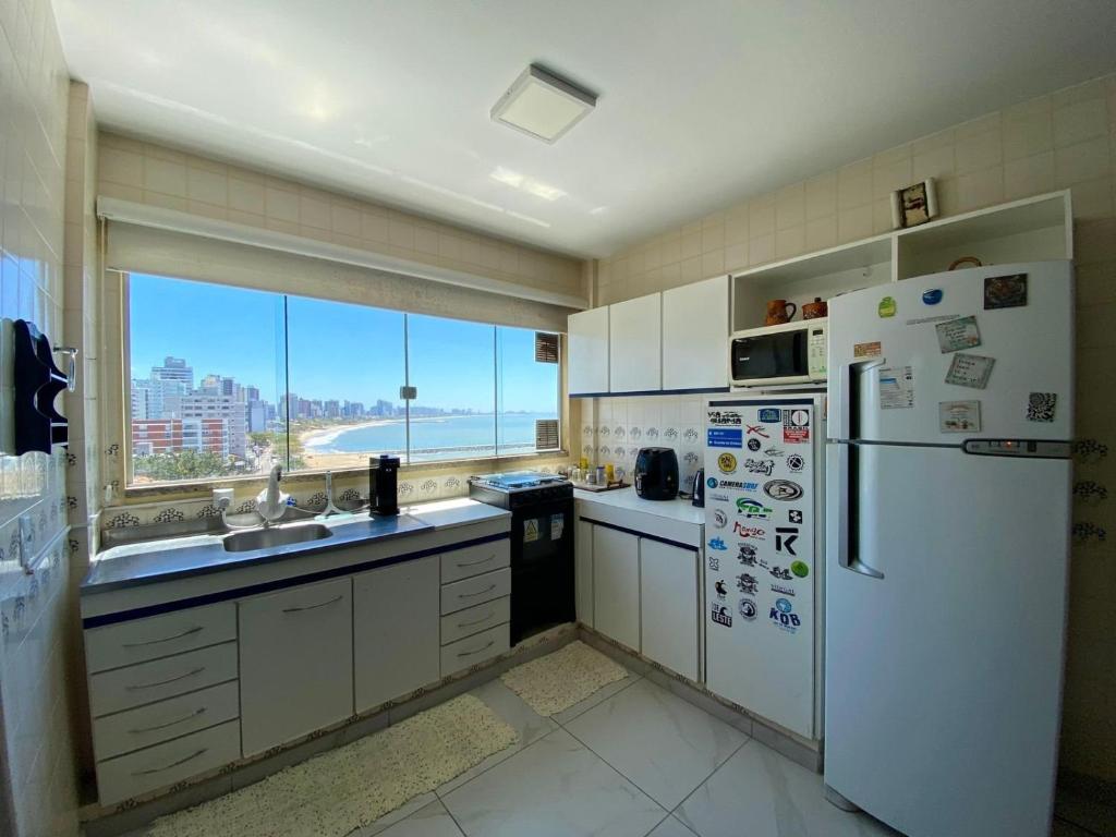 cocina con electrodomésticos blancos y ventana grande en Apto Confortável p/ até 9P, 50mts do mar Piçarras, en Piçarras