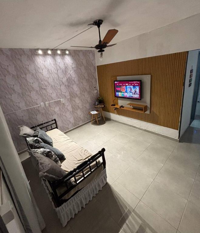 a living room with a couch and a tv on a wall at Refúgio Pérola Capixaba in Marataizes