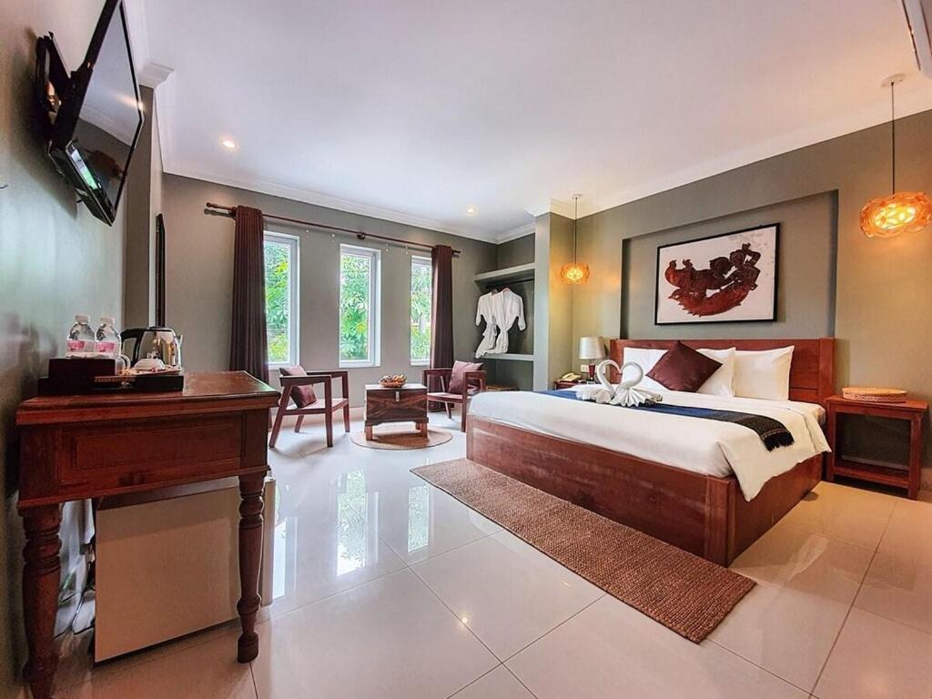 a bedroom with a bed and a desk and a piano at Siem Reap ABACUS Hotel in Siem Reap