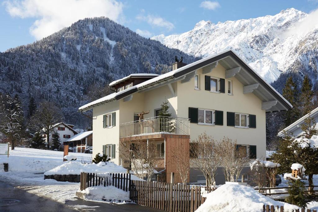una casa nella neve con montagne sullo sfondo di Haus Topa a Vandans