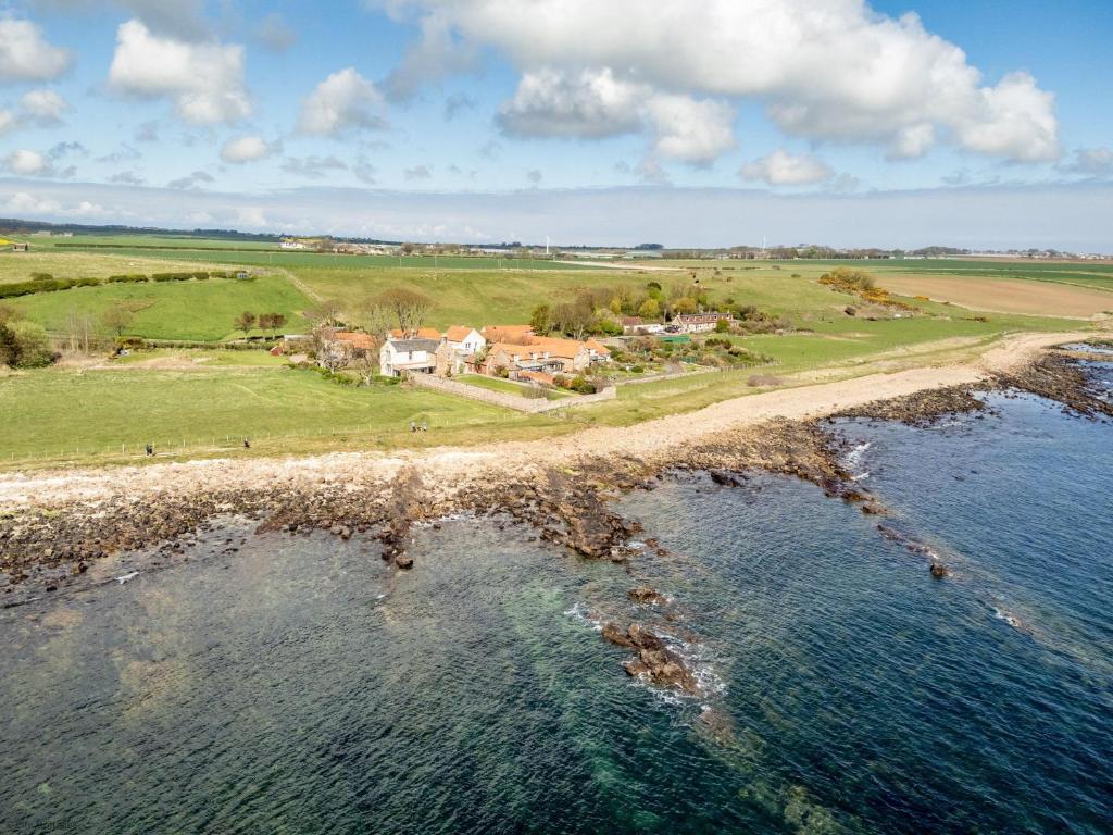 an aerial view of a house next to the ocean at Caiplie Farmhouse, Caiplie, by Crail, KY10 3JR in Kilrenny