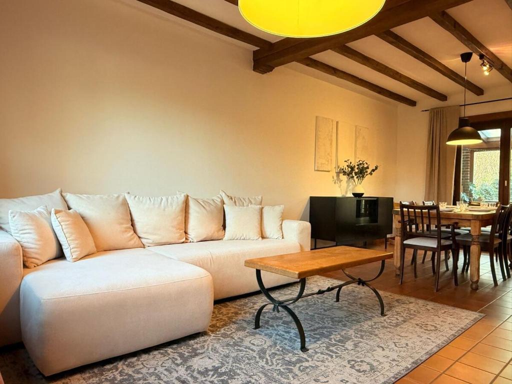 uma sala de estar com um sofá branco e uma mesa em Maison spacieuse avec jardin à Soignies em Soignies