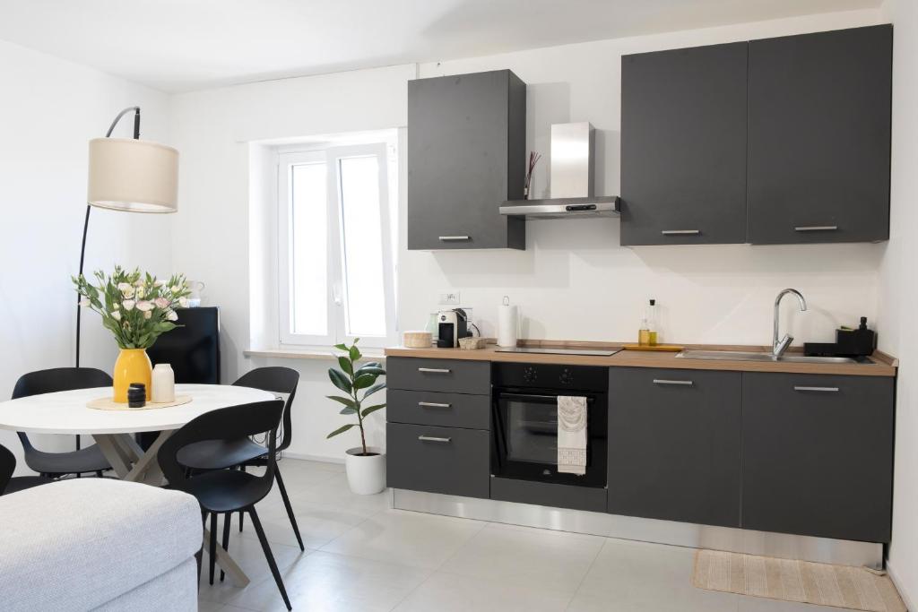 eine Küche mit schwarzen Schränken und einem Tisch und einem Tisch und Stühlen in der Unterkunft Rosmaris - Villa nel verde in Francavilla al Mare