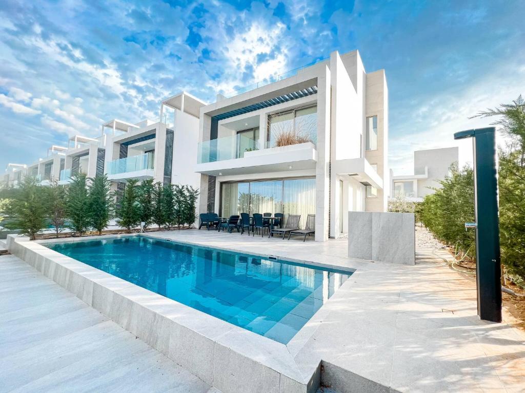 a villa with a swimming pool in front of a house at Azure Villas by Marc in Paralimni